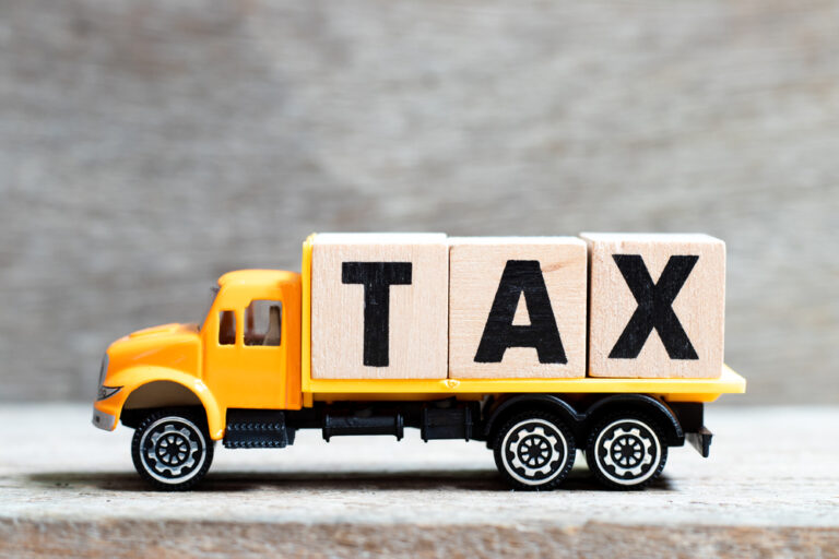 Yellow toy truck with TAX blocks representing HVUT tax form 2290